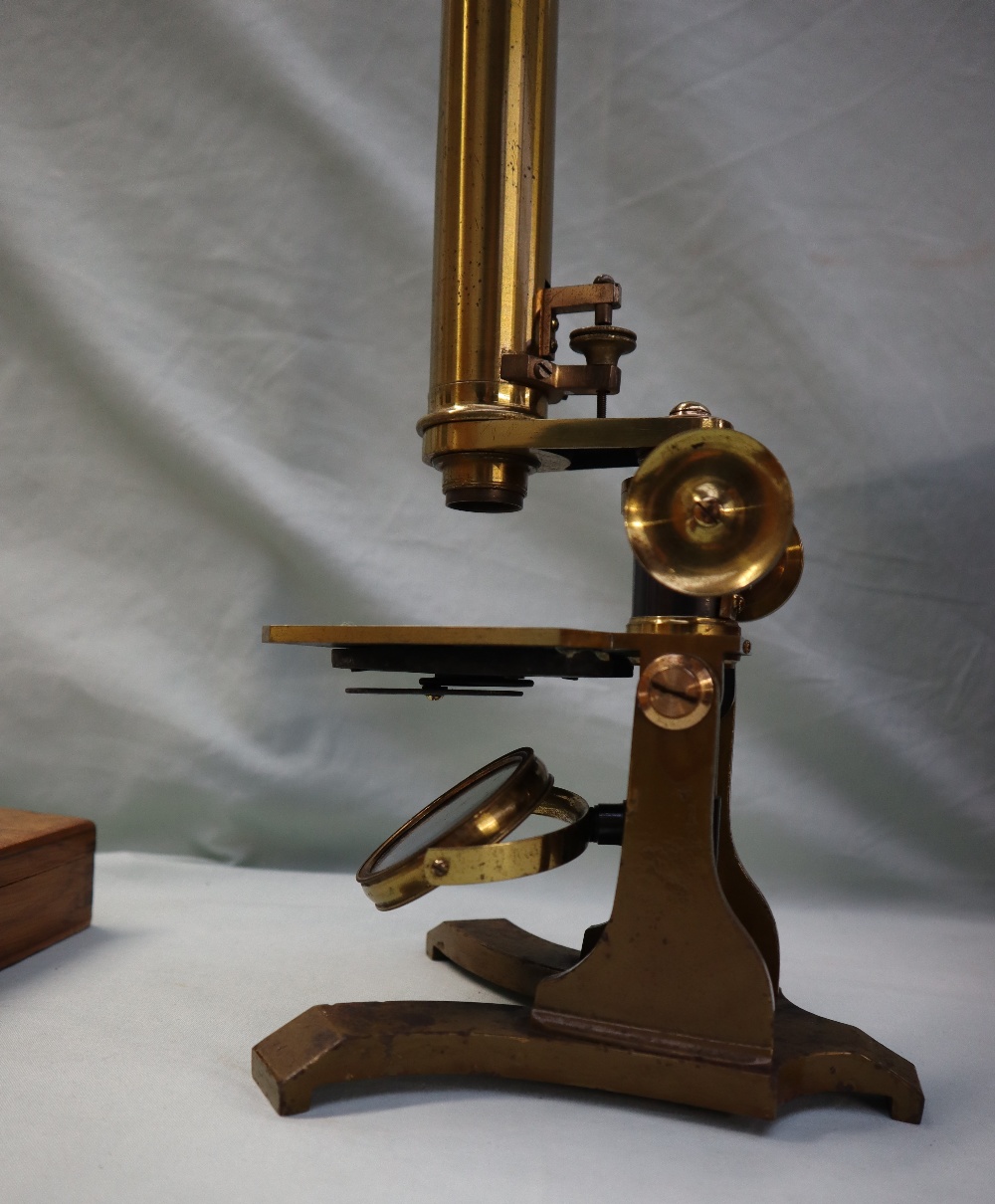 A brass monocular microscope, with rotating mirror, adjustable platform