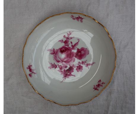 A Meissen porcelain shallow dish, with a gilt rim, painted to the centre with a spray of roses and garden flowers in puce, un