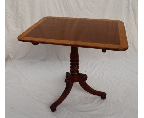 A George III mahogany tripod table with a crossbanded top on a snap action and baluster column with three scrolling legs and 