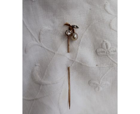 A yellow metal stick pin, set with two round old cut diamonds and a pearl, of leaf form, approximately 2.5 grams