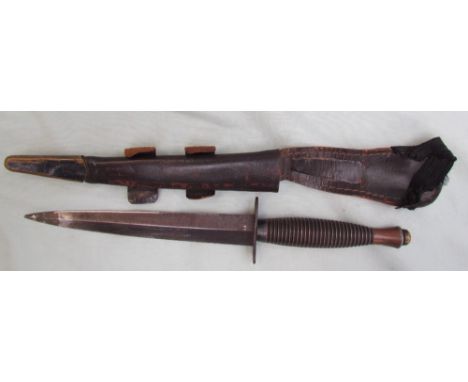 A Commando knife, with a ribbed handle, with a tapering blade in a leather scabbard, 290.5cm long, blade 17.5cm long
