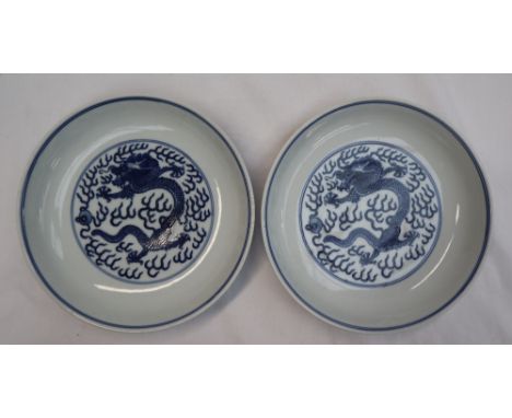 A pair of Chinese porcelain dishes, decorated with dragons amongst clouds,  "Ching" dynasty marks to the base, 18.5cm diamete