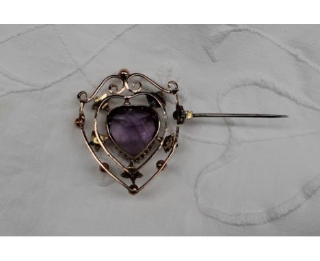 An amethyst and seed pearl brooch of shield shape, the central heart shaped amethyst approximately 15mm x 9mm, surrounded wit