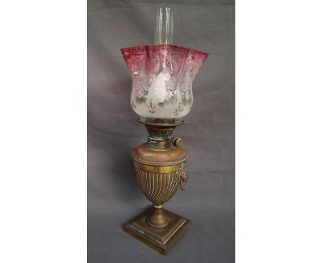 A Victorian oil lamp, the graded etched glass shade, above an urn shaped body with lion mask handles on a square base, conver