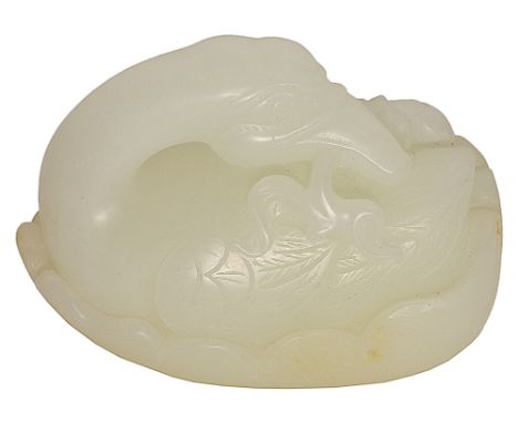 A CHINESE WHITE JADE GOOSE carved resting on a large lotus leaf, the crested head turned sharply back over the neatly folded 