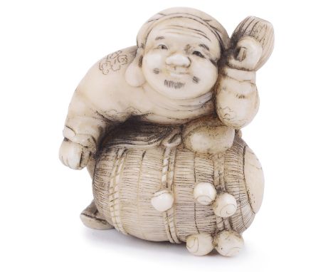 ˜WALRUS IVORY NETSUKE OF THE LUCKY GOD DAIKOKU WITH HIS RICE BALE, CIRCA 1870 unsigned 3.8cm high Provenance: The Netsuke Col