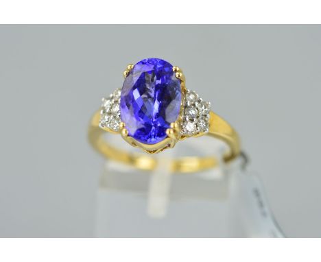 A MODERN TANZANITE AND DIAMOND RING centring on an oval mixed cut tanzanite measuring 11.5mm x 7.8mm, ten modern round brilli