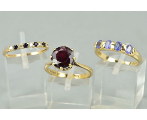 THREE 9CT GOLD RINGS to include a circular garnet ring, a tanzanite four stone ring and a sapphire and cubic zirconia nine st