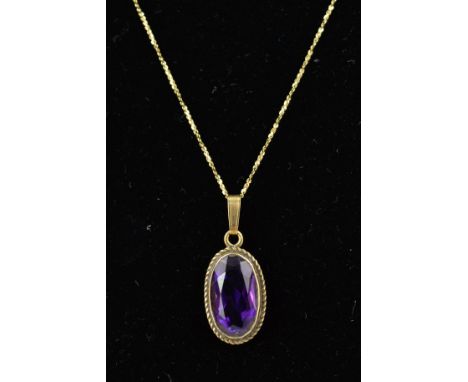 A 9CT GOLD AMETHYST PENDANT AND CHAIN, the oval amethyst within a collet setting with rope twist surround, suspended from a f