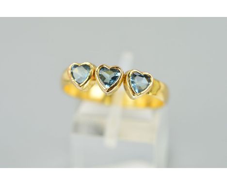 A THREE STONE RING designed as three heart shaped, collet set blue pastes to the plain band, ring size U, weight 2.2 grams