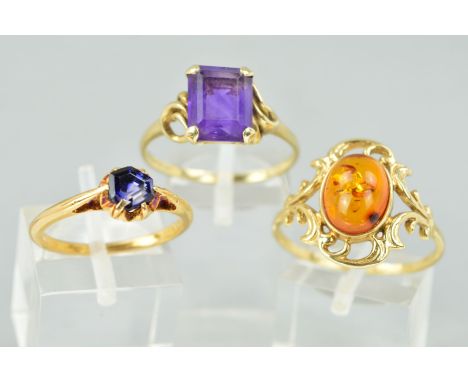 THREE DRESS RINGS comprising of an amber single stone with scroll decoration, a rectangular single stone amethyst ring and a 