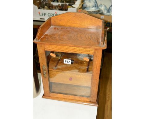 AN OAK PIPE SMOKERS CABINET with a central drawer and glazed hinged door, approximate height 37cm (no key)