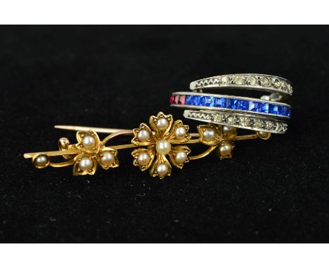 AN EARLY 20TH CENTURY 15CT GOLD BROOCH AND A HINGED PASTE RING, the brooch designed as a flower and leaves set with split pea