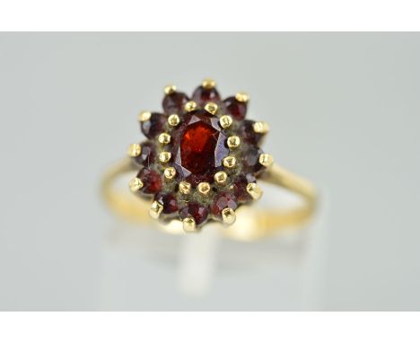 A 9CT GOLD GARNET CLUSTER RING designed as a central oval garnet within a circular garnet surround, hallmark for Birmingham, 