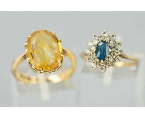 TWO 9CT GOLD RINGS, the first designed as an oval citrine within a claw setting, ring size M, the second a tiered topaz clust