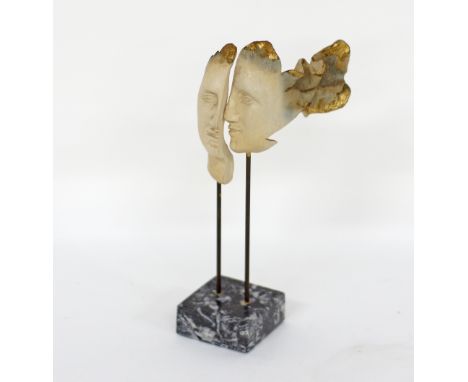 A modern ceramic sculpture of a face, on metal poles, on black marble plinth. H26cm.