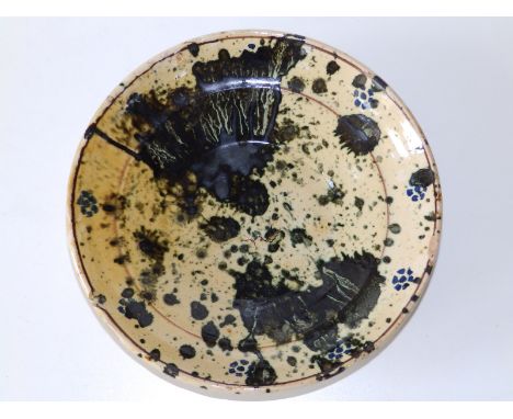 A splash glazed ceramic bowl in blue on cream ground, the moulded cavetto with thin dark brown line borders, the abstract pat