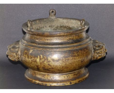 An antique Chinese gilt bronze censer with lion mask handles, the waisted rim having three small projecting loops, the rounde
