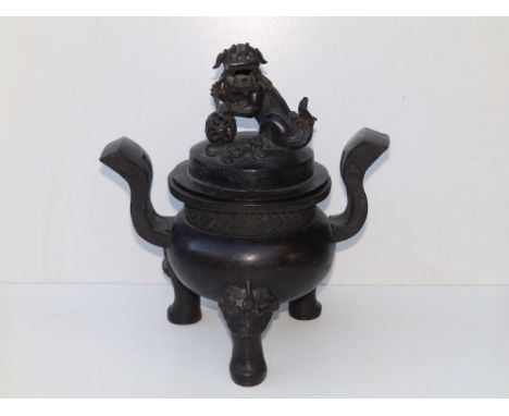 An antique Chinese bronze covered censer, the cover surmounted by a Buddhistic lion, the rounded base having a band of fret d