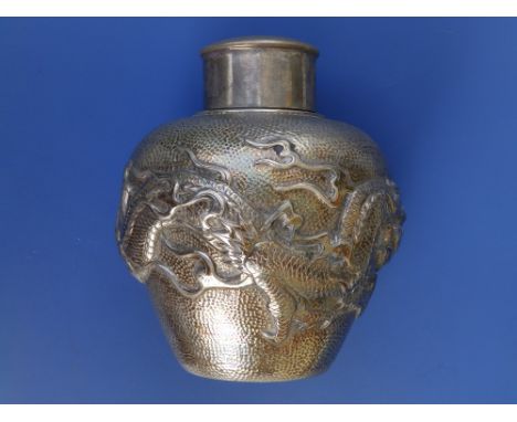 A late 19thC Chinese silver tea caddy with cover, of round shouldered form, the embossed decoration showing a single dragon e