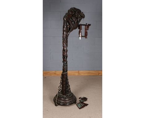 Chinese carved hardwood standard lamp, having heavily carved dragons head and column, the shade in the form of a lantern, rai