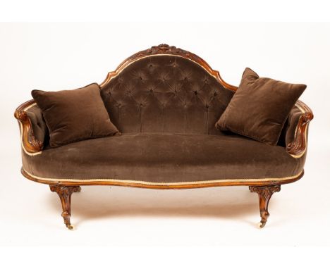 A small Victorian carved walnut sofa with arch back and carved scroll arms, the serpentine front raised on carved scroll legs