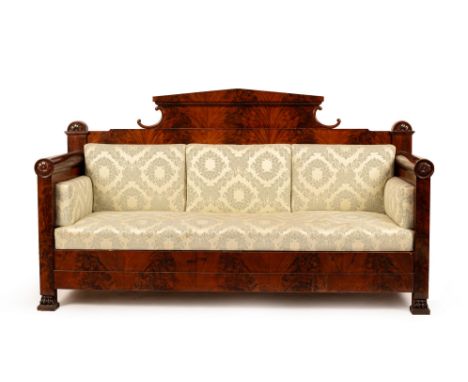 A Biedermeier flame mahogany sofa, with architectural crest rail, the side supports with rosette motifs to the top and on paw