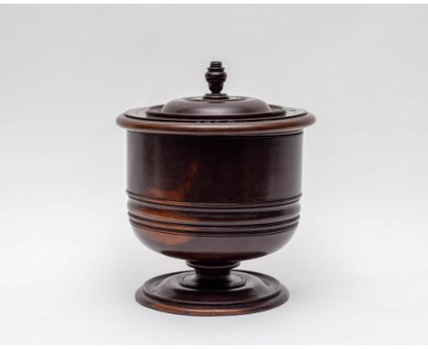 A lignum vitae wassail bowl and cover, 17th Century, the cover with urn finial and holes for dipping-cup pegs, 23cm diameter,