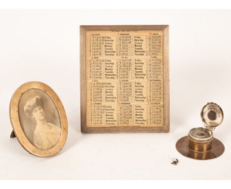 A silver frame, Asprey, London 1927, with engine turned decoration containing a perpetual calendar, 24.5cm x 20.5cm, an oval 