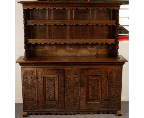 A large 19th Century Spanish oak dresser, the superstructure with a moulded cornice above two plate shelves with shaped apron