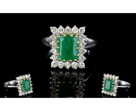 18ct White Gold Emerald and Diamond Set Cluster Ring of Nice Quality. The Central Step Cut Emerald of Good Colour, Surrounded