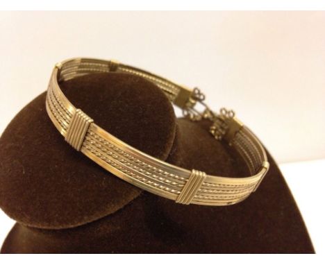 A fancy gold bangle with safety chain. 14ct gold plated.