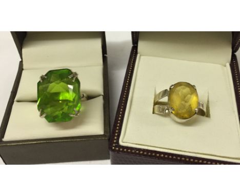 2 silver rings with very large stones. One set with a green stone Size R, the other with yellow stone size Q.