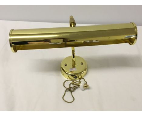 A gold coloured metal wall light for pictures.