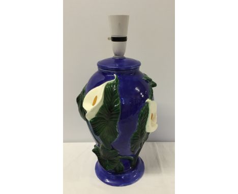 A large blue ceramic table lamp with raised Arum Lily decoration.