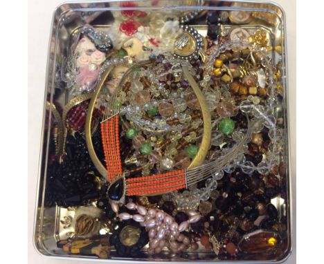 A tin of vintage costume jewellery including stone and glass bead necklace, brooches and earrings.