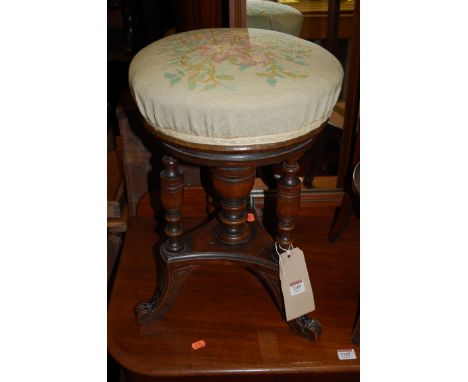 An Edwardian walnut music stool, having tapestry upholstered circular revolving top