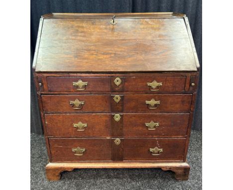 18th century oak bureau, the rectangular surface with gallery moulding above a sloped drop front opening to an arrangement of
