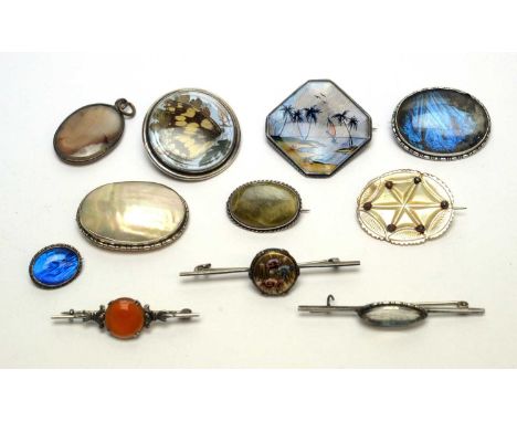 A selection of silver and other brooches, set with mother of pearl, butterfly wings and other items. 