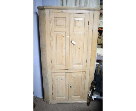 A 19th Century stripped pine floor standing corner cupboard, the upper section with a pair of panelled doors, enclosing pierc