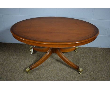 A reproduction oval yew wood pedestal coffee table, by Bradley Furniture, raised on a quadripartite support, with four reeded