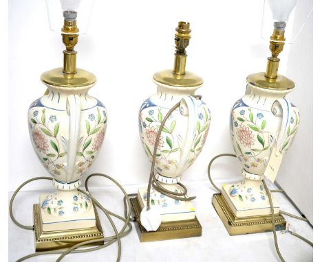 A set of three floral decorated twin-handled urn vase table lamps, each raised over a square form metal base, approximately 4