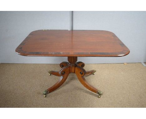 A Georgian mahogany and rosewood banded tilt-action breakfast table, rounded rectangular, raised on reeded column, reeded and