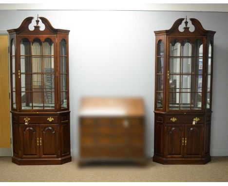 Tell City Chair Company: a pair of 'Tidewater Cherry' corner display cases, 20th Century, each with swan neck pediment and ur