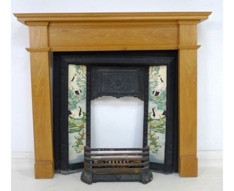 A Victorian cast iron fire surround inset with ten modern tiles decorated with cranes and bamboo, with modern oak surround an