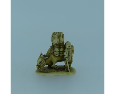 An antique Japanese Ivory Netsuke, depicting a figure leading a laden water buffalo, no signature, 3.5cm long, together with 