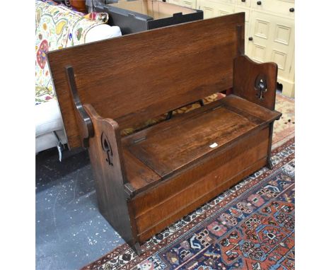 An Arts and Crafts period monks bench, the top hinging over to form a seatback, over a box seat with hinged panel enclosing a