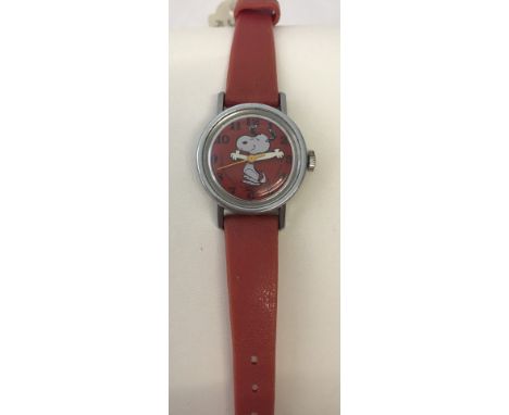 A vintage Timex Snoopy by Schultz wristwatch with original red plastic strap. With moving Snoopy arms. Face marked copyright 