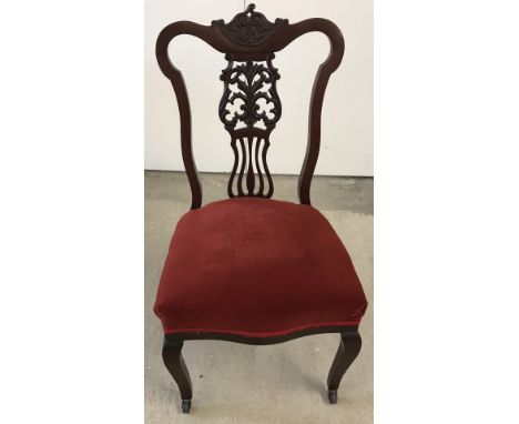 A Victorian bedroom chair with decoratively carved back, ceramic castors and velvet upholstered seat  