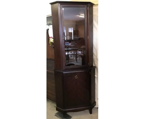 A Stag dark wood corner display cupboard with interior glass shelves and lighting.  Approx. 73cm wide x 183cm tall.